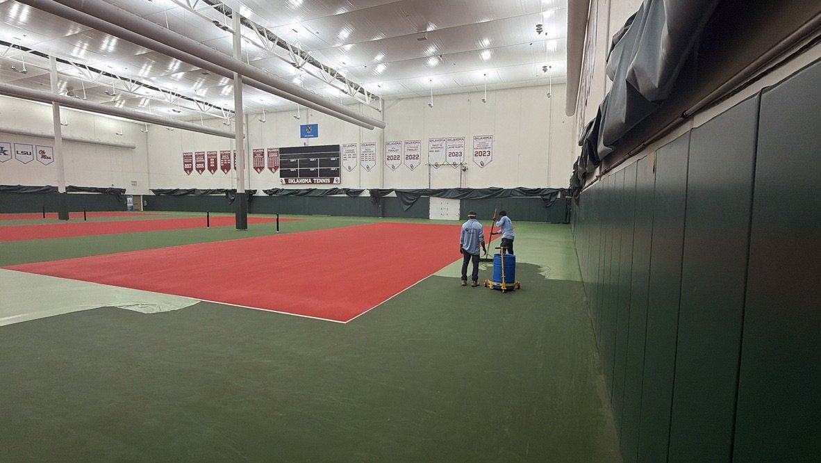 Indoor court at the Gregg Wadley Pavilion with the red playing area freshly squeegeed and the green surround going on